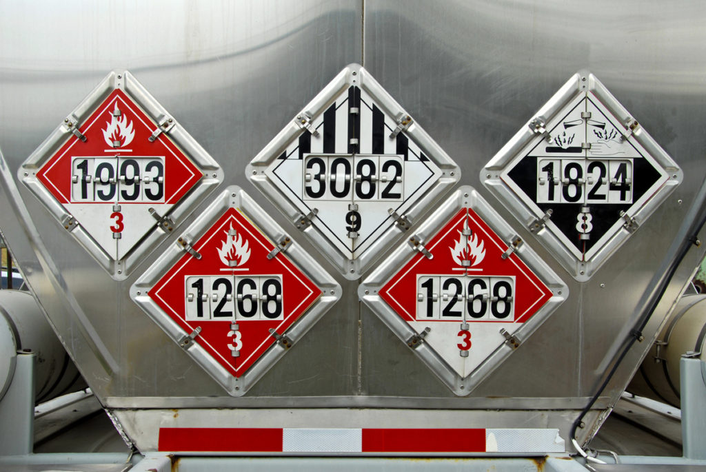 Rear of tanker truck with hazardous materials signs displayed.