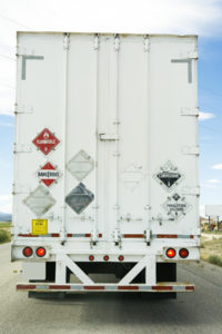 Rear of 18-wheeler trailer with hazardous materials signs displayed.